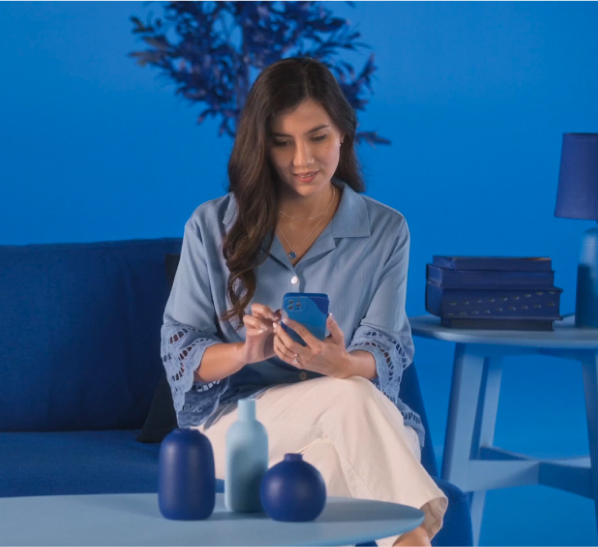 A woman in a blue-tinted office environment interacts with her smartphone.