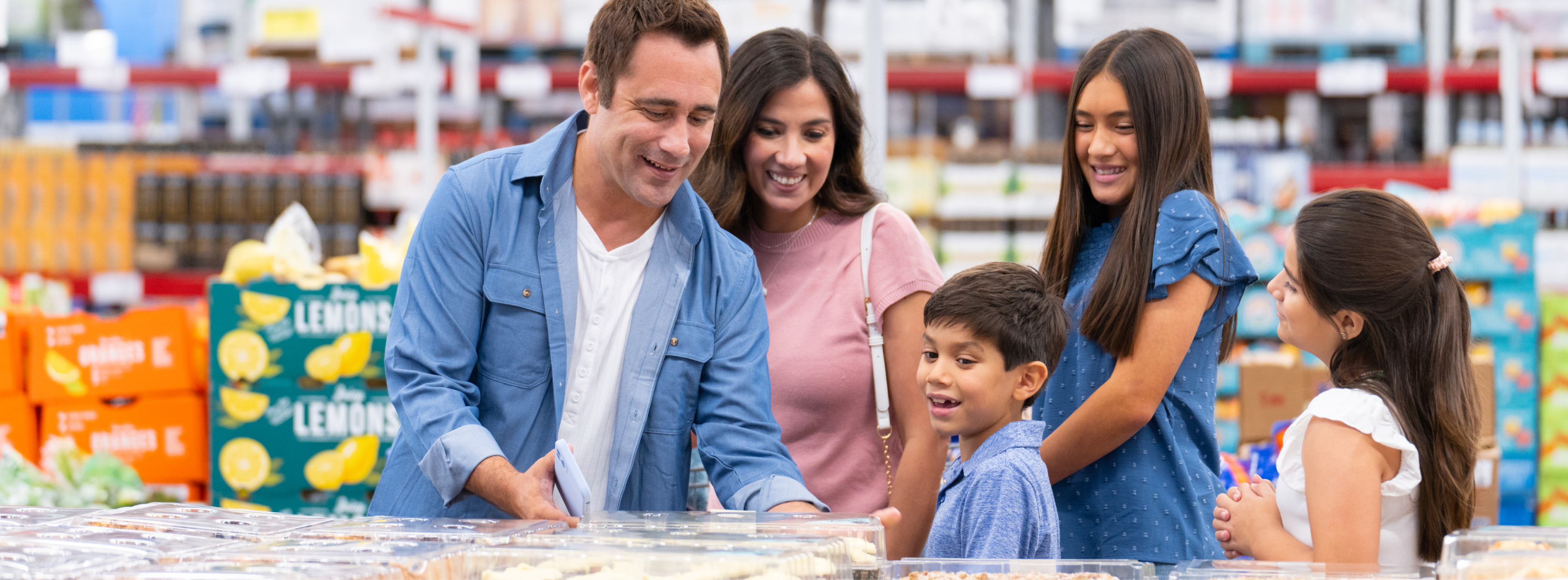 A family examines the shelves of items in a Sam's Club.