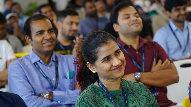 A smiling female audience member. Behind her are two smiling male audience members. 